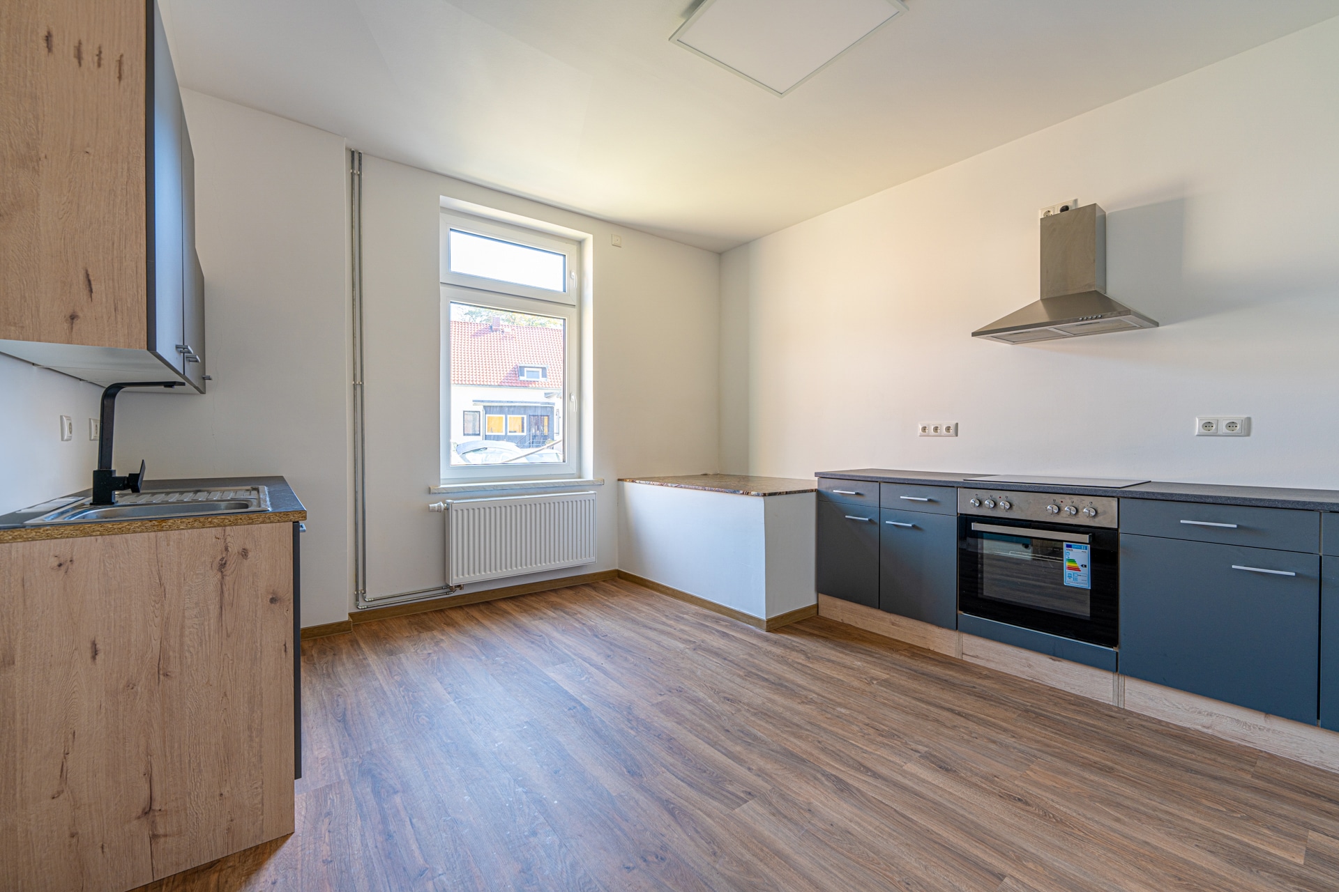 Leere Küche mit Holzfußboden und Fenster.