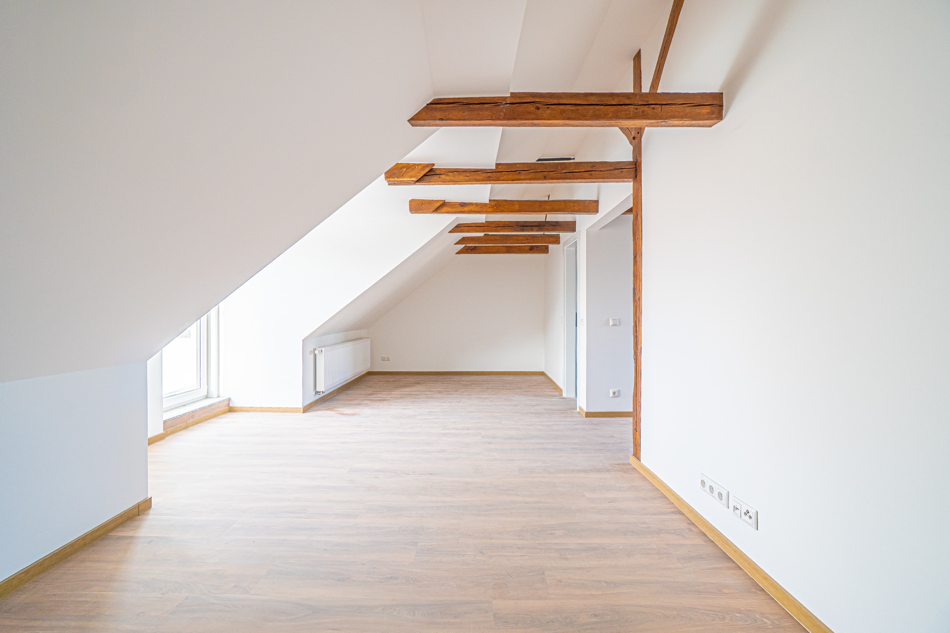 Dachgeschosswohnung mit Holzbalken, leeres Zimmer.