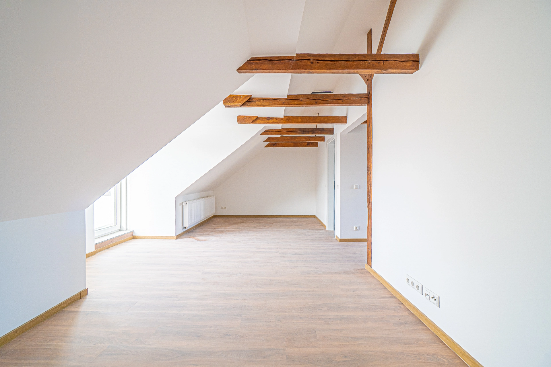 Dachgeschosswohnung mit Holzbalken, leeres Zimmer.